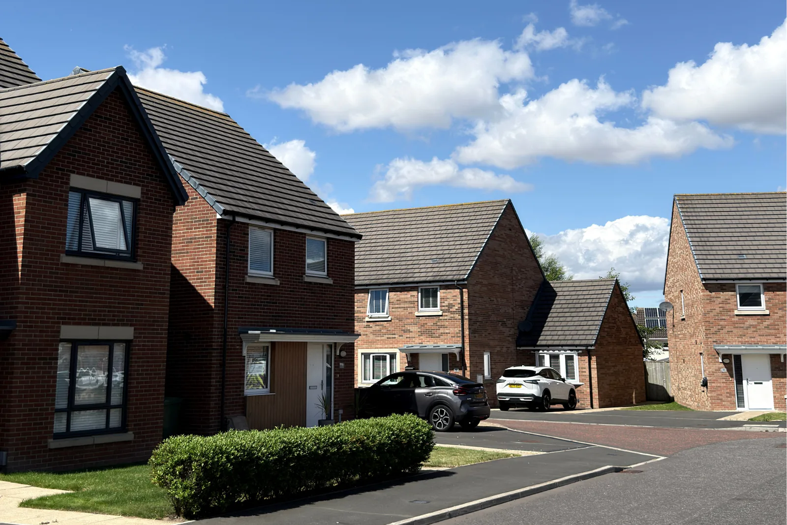 Modern red-brick homes on a residential street under a blue sky